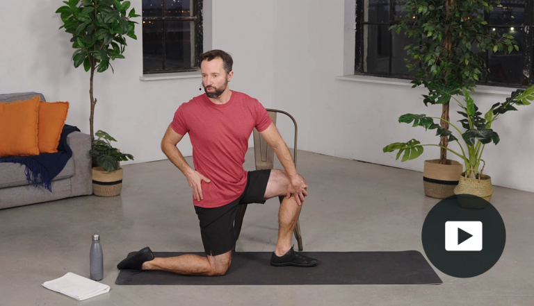 Farrell Kaufman doing a twist on one knee on a mat in a room with plants, with video icon overlay 