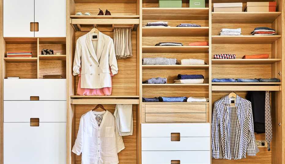 very organized wood and white closet with clothes neatly folded on shelves and hanging