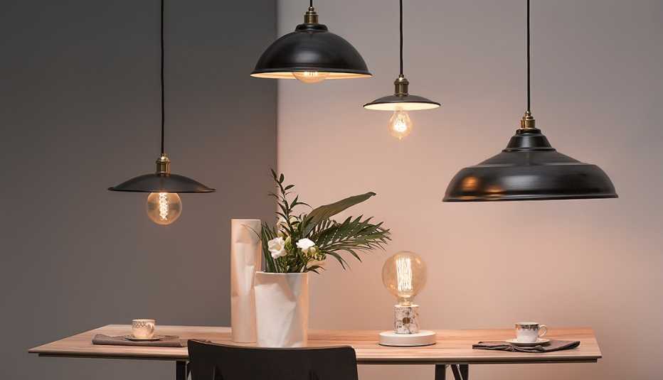 a dining table with four back overhead lamps of different shapes and sizes
