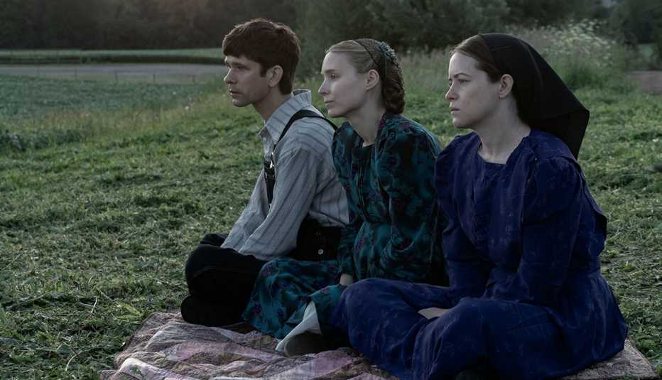 three people sitting on blanket in grass in a still from women talking
