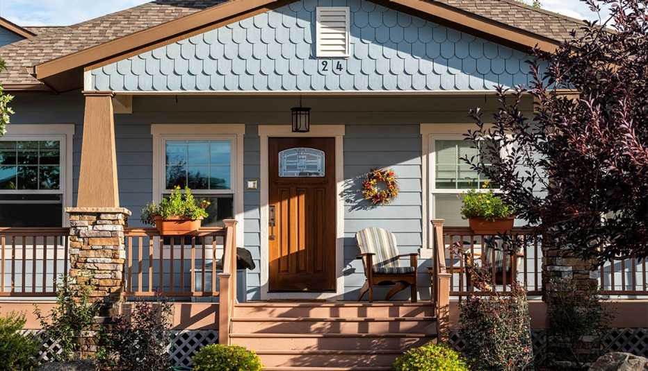blue craftsman-style house with an inviting front porch with plants and adirondack chair