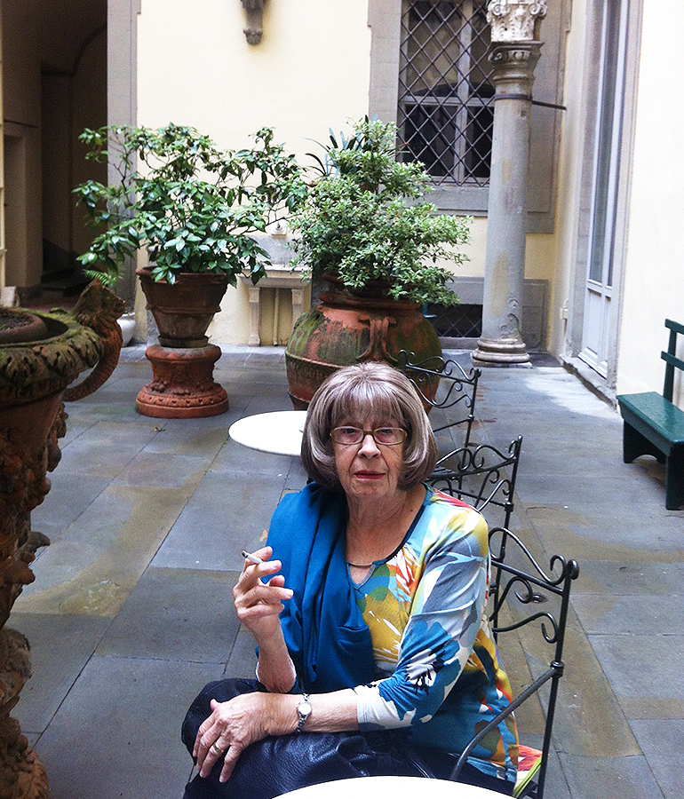 Ann Hood's mother, Gogo, sitting in a chair holding a cigarette in a courtyard in Italy