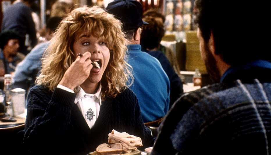 sally albright (meg ryan) sits across from harry burns (billy crystal) and puts a forkful of food in her mouth in famous diner scene from movie when harry met sally