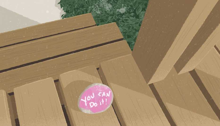 A small rock, painted pink, with the words “You can do it” painted in bright white letters sits on a wooden porch