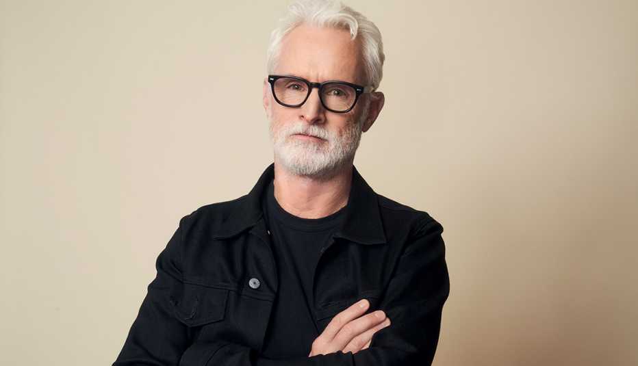 john slattery with arms crossed in front of off white background