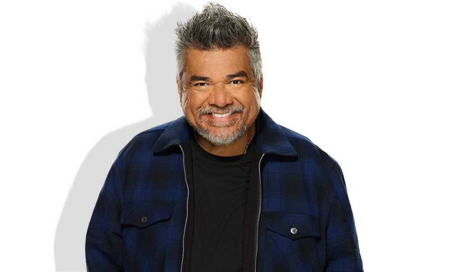 george lopez in black shirt and blue and black jacket against white background
