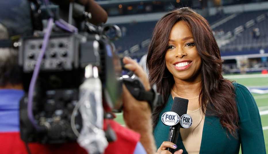 Pam Oliver reports on camera while from the sidelines.