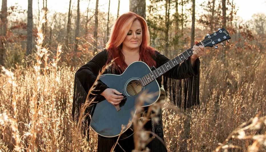 wynonna judd playing guitar surrounded by trees