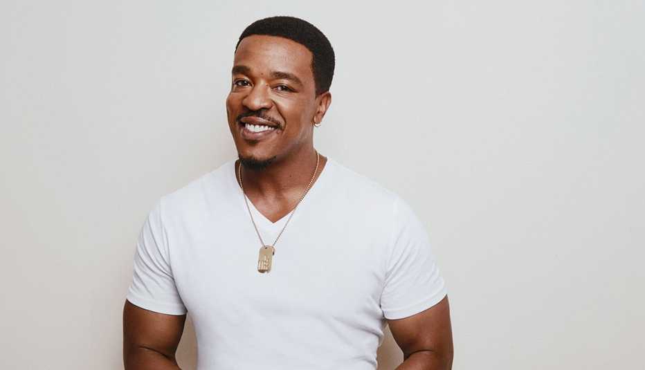 Russell Hornsby poses wearing a white T-shirt with dogs tags on a necklace.