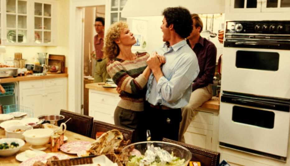 Glenn Close and Kevin Kline dance in a messy kitchen in scene from 'The Big Chill,'  with William Hurt and Jeff Goldblum in the background,