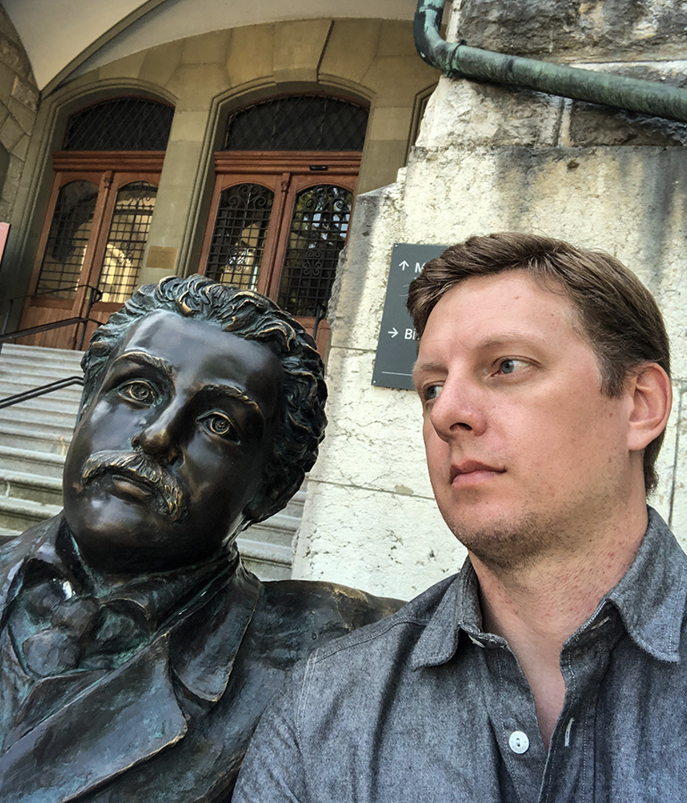 Ryan Krogh poses with a statue of Albert Einstein outside a building in Switzerland