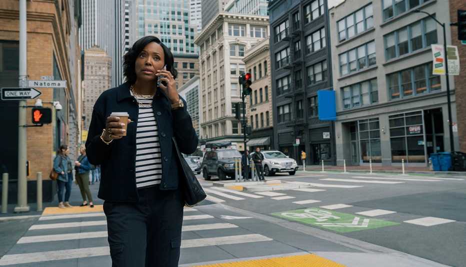 aisha tyler walking on city street talking on phone, holding coffee in a still form the last thing he told me