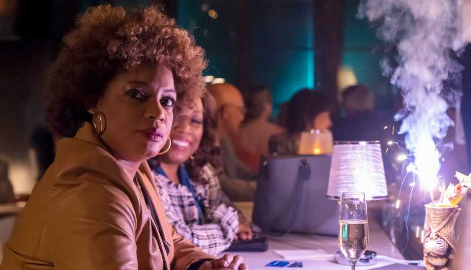 aunjanue ellis as carolyn wilder sitting at table with champagne glass in front of her in justified city primeval