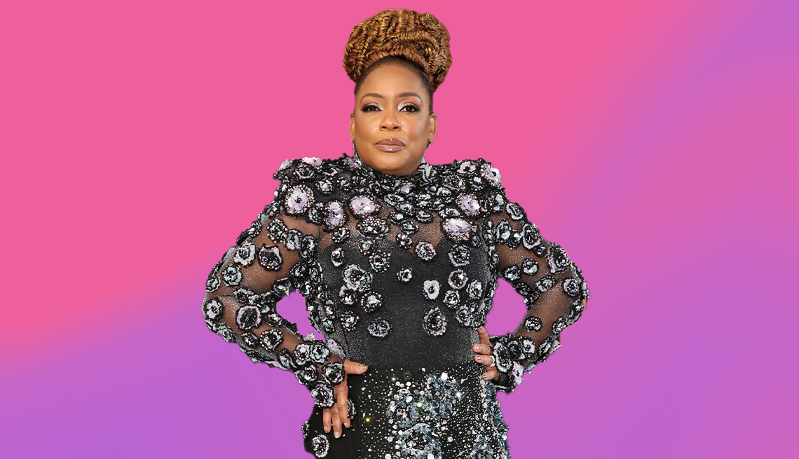 aunjanue ellis in black sparkly outfit with hands on hips against pinkish purple background