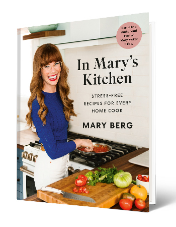 book cover with words In Mary’s Kitchen: Stress-Free Recipes for Every Home Cook; woman cooking  with pan on stove and vegetables on table