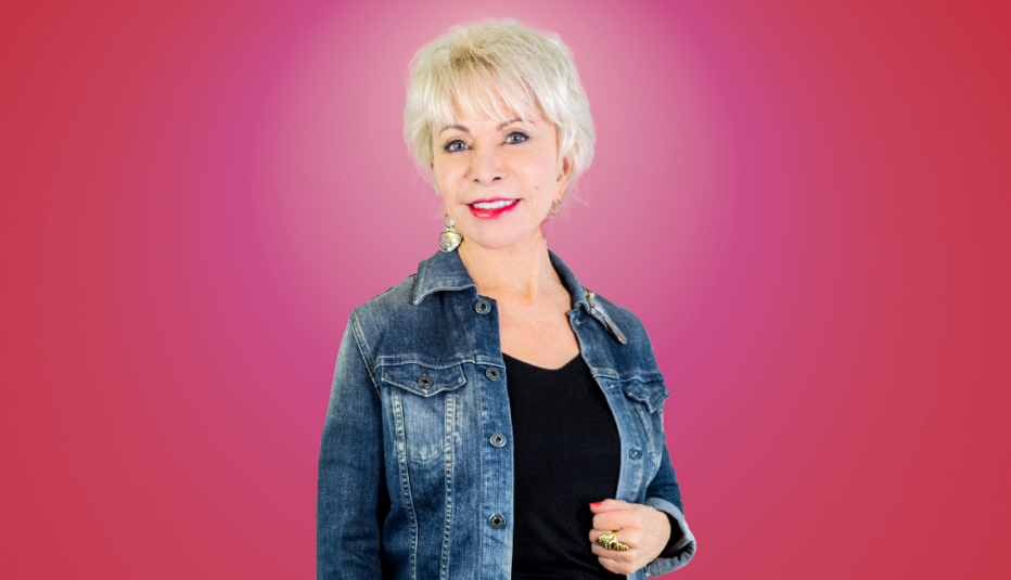isabel allende wearing a blue jean jacket and smiling against a pink background