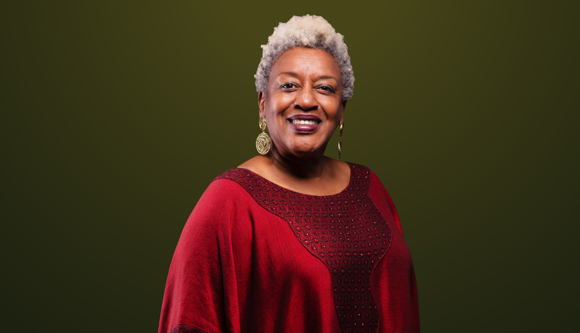 CCH Pounder smiling and wearing a red dress against a dark green background