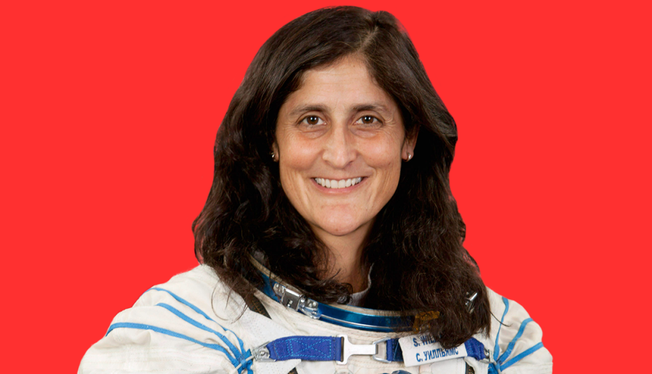 headshot of sunita williams wearing astronaut uniform against red background