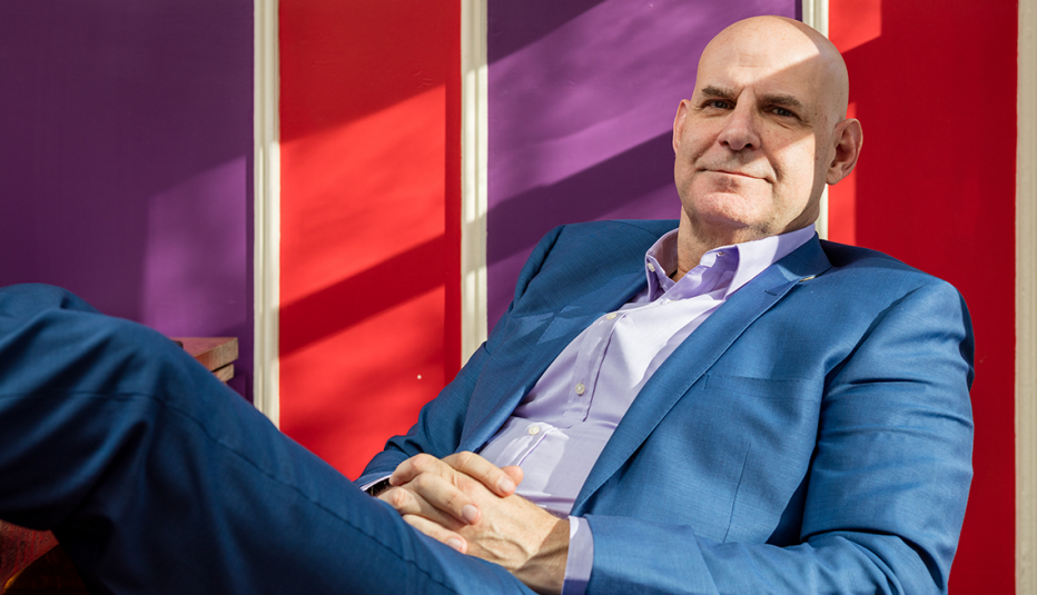 harlan coben sitting, leaning back, with feet up and hands together