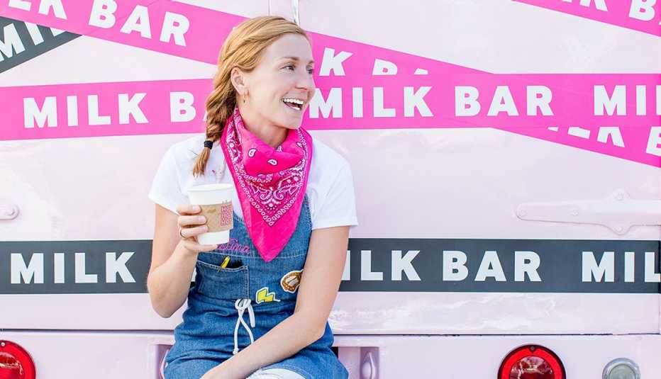 christina tosi holding cup; several ribbons with the words milk bar on them behind her