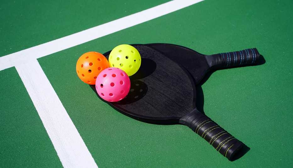 two pickleball paddles and three balls on court