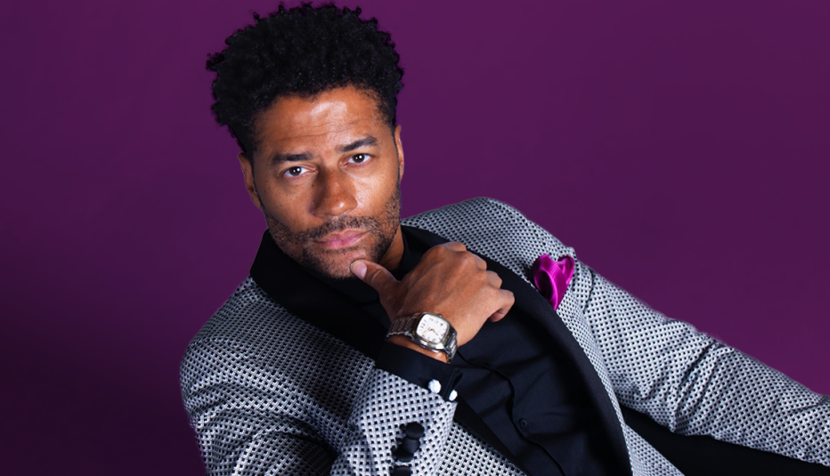 eric benet leaning back with thumb against chin; purple background