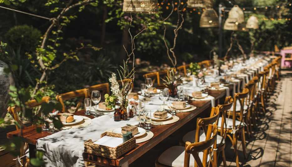 long wooden table with plates, glasses, napkins, silverware 