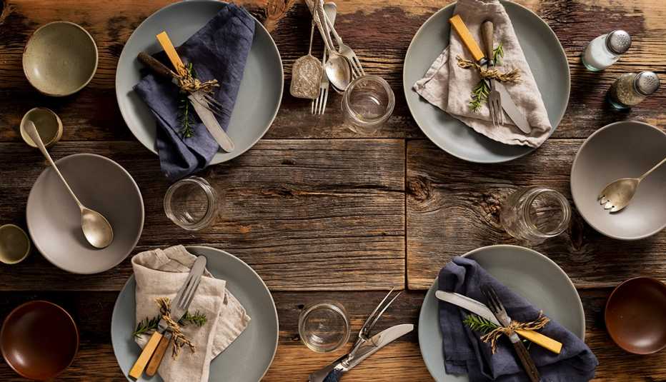 rustic dinner party table setting with plates, silverware, napkins and glasses
