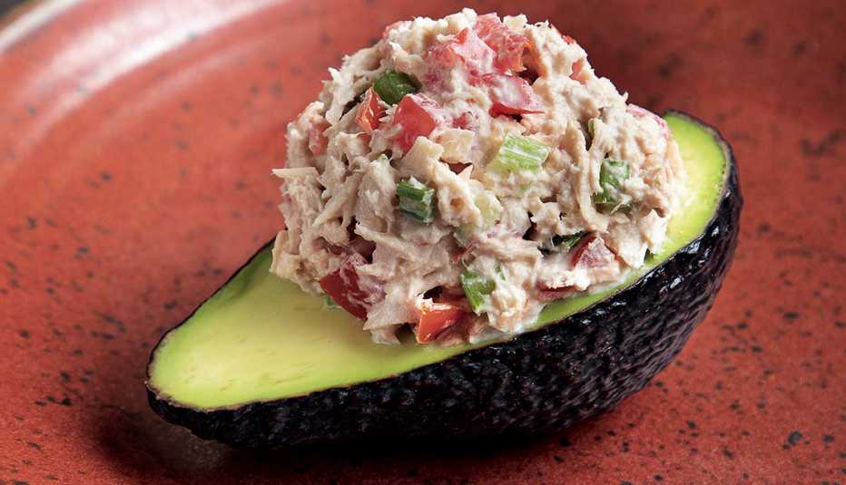 palta reina de atún from latinísimo cookbook showing half an avocado with a scoop of tuna on top mixed with chopped tomato, celery and green onion