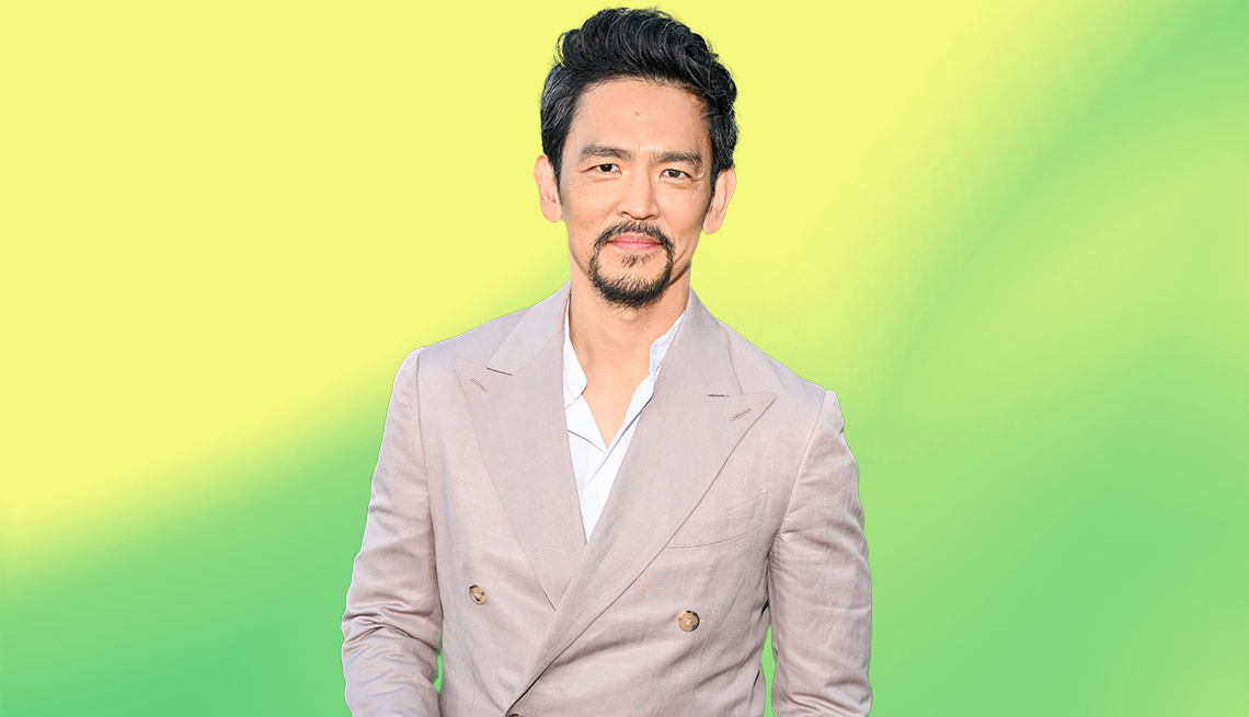 john cho in tan suit jacket against yellow and green ombre background
