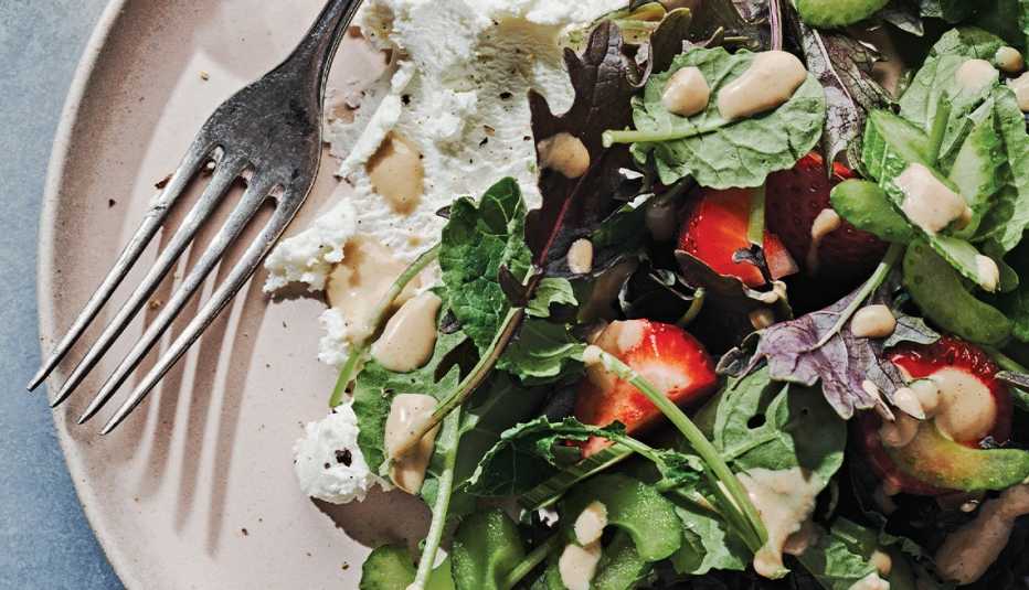 salad with kale, strawberries, celery, pecans and cheese on plate with fork