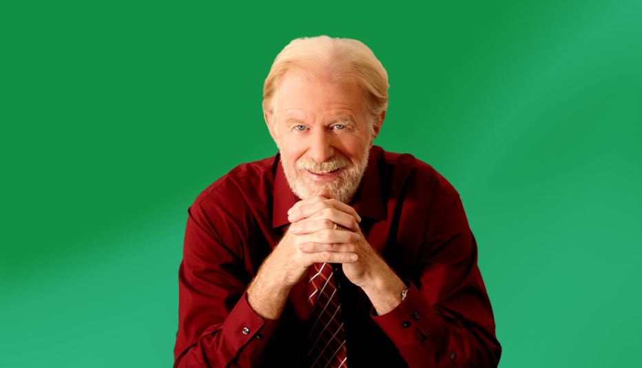 Ed Begley Jr. with hands under chin against green ombre background