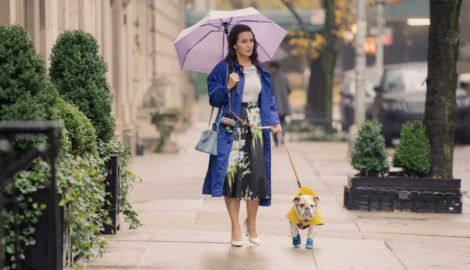kristin davis as charlotte york holding umbrella, walking dog on sidewalk in a still from and just like that