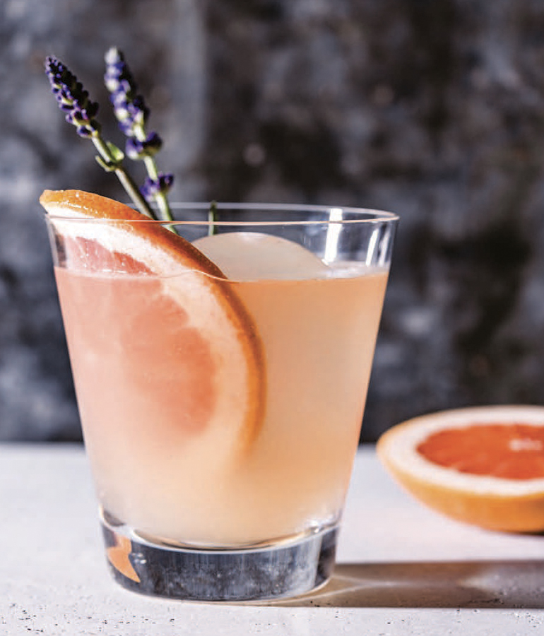 lavender paloma in glass with grapefruit slice and sprig of fresh lavender in it