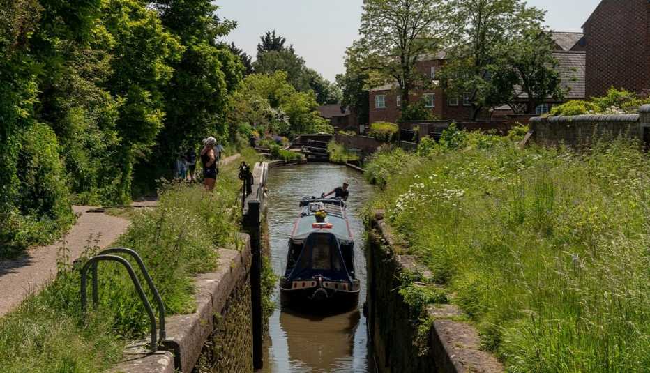 boat making its way through a lock on the stratford-upon-avon canal; trees and high grass surround canal