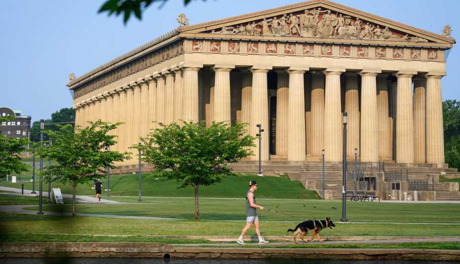woman walking dog in front of parthenon at centennial park 