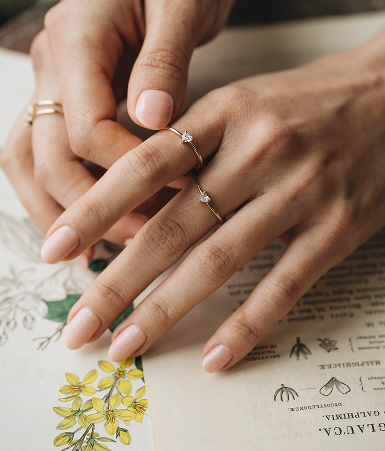 two hands with rings on them on piece of paper with writing and flowers on it