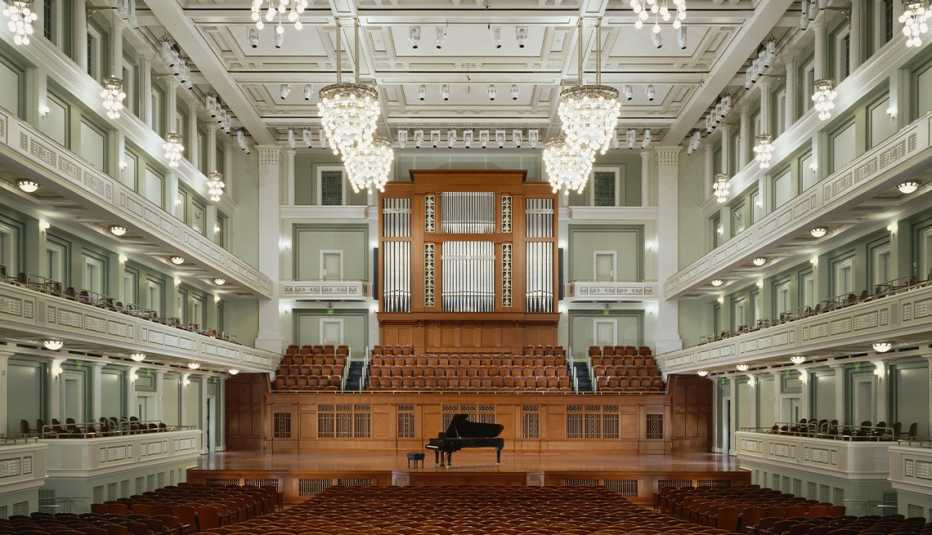 Inside of concert hall; stage with piano in center and seats above; seats on two levels around the concert hall