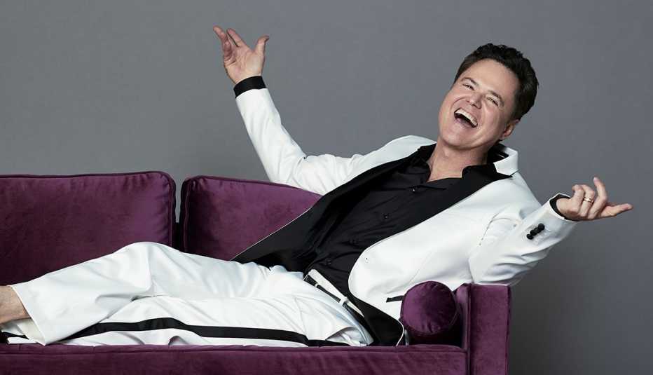 Donny Osmond lies on a couch