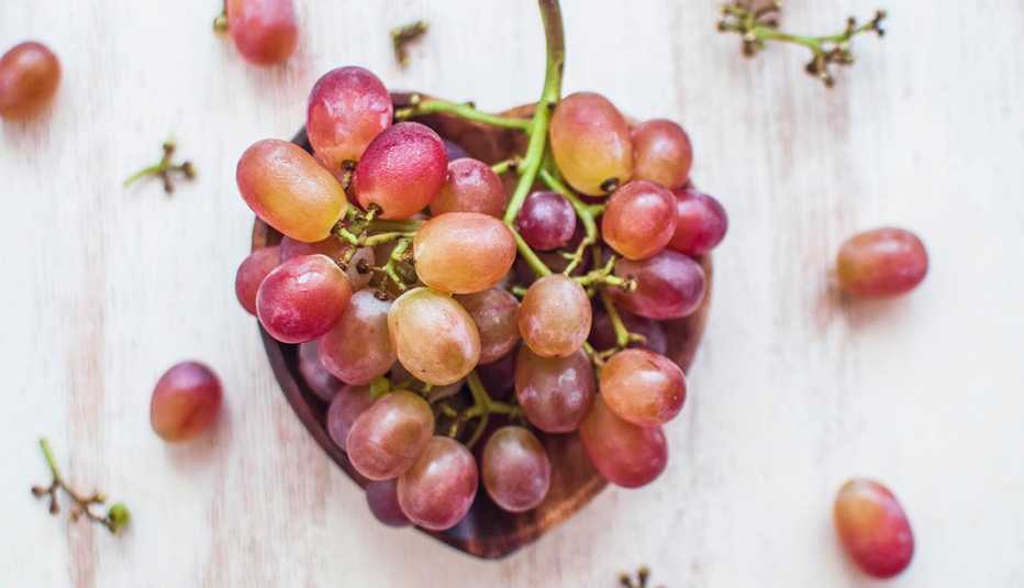red grapes in and around a heart-shaped bowl
