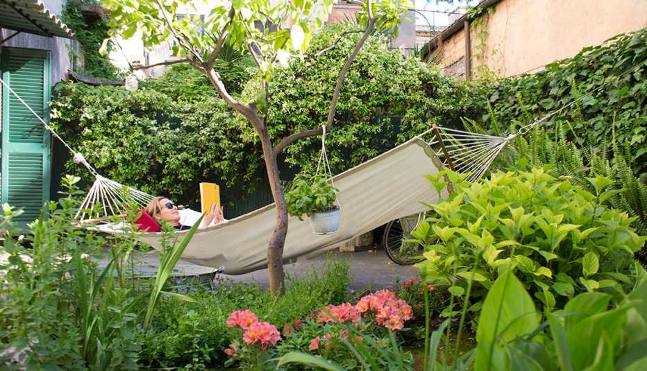 person lying in hammock outside, surrounded by shrubs, plants and flowers