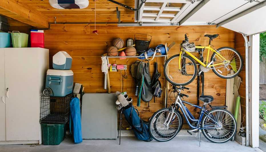 garage with cabinet, baskets, coolers, crate, basketballs, golf clubs, tennis rackets and bicycles