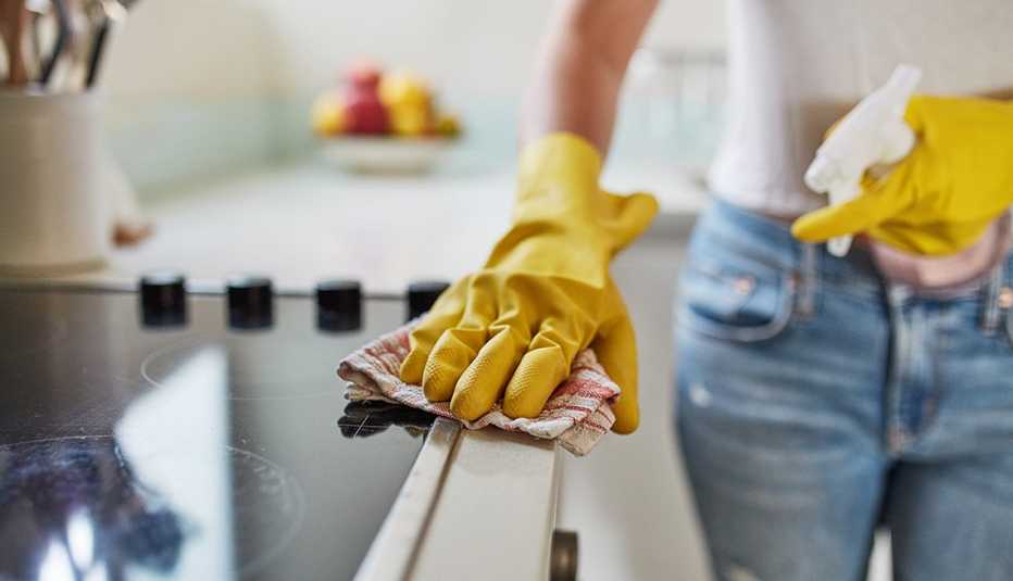 person wearing yellow gloves cleaning stovetop