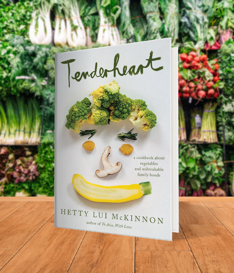 cookbook that says tenderheart with vegetables making a face; on wooden table with vegetables and plants behind it