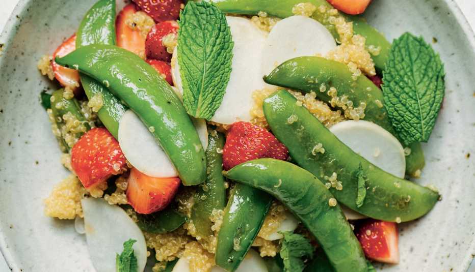 salad with mint leaves, sugar snap peas, turnips, strawberries and quinoa in bowl