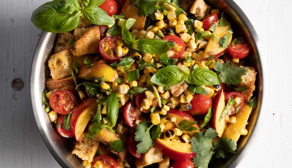 salad with tomatoes, herbs, nectarines and corn in a bowl