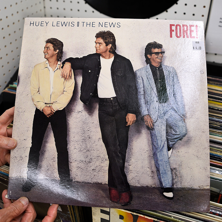 Person holding a record album with words Huey Lewis and the News, Fore 