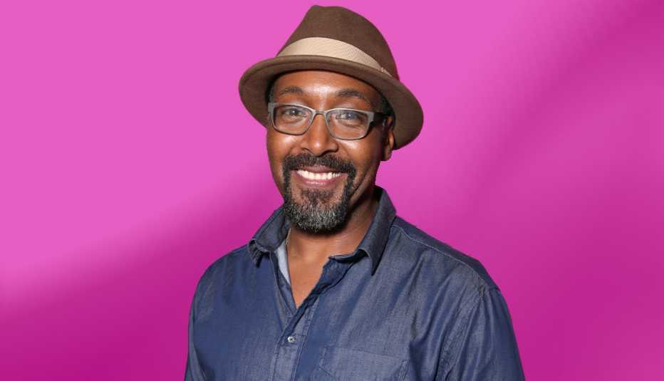 jesse l martin wearing hat against pink ombre background