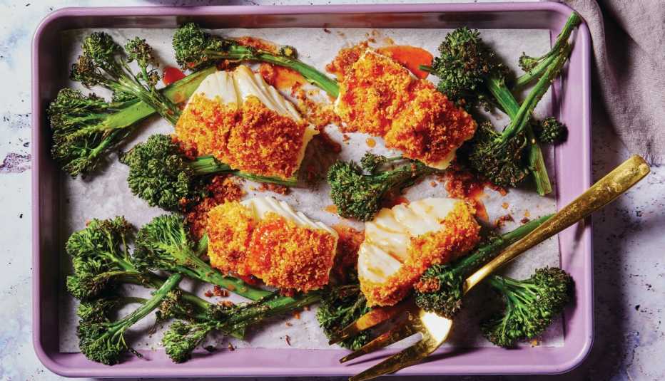 coconut-crusted fish with honey-chili drizzle next to broccolini on baking sheet