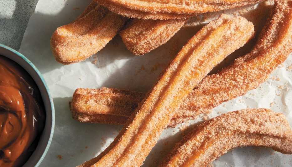 Churros next to a bowl of brown dipping sauce